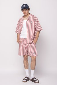 Rød og hvit stripet kortermet skjorte og matchende shorts, blandingsvaskerstoff, avslappet passform, brukt med en marineblå caps og brune sandaler.