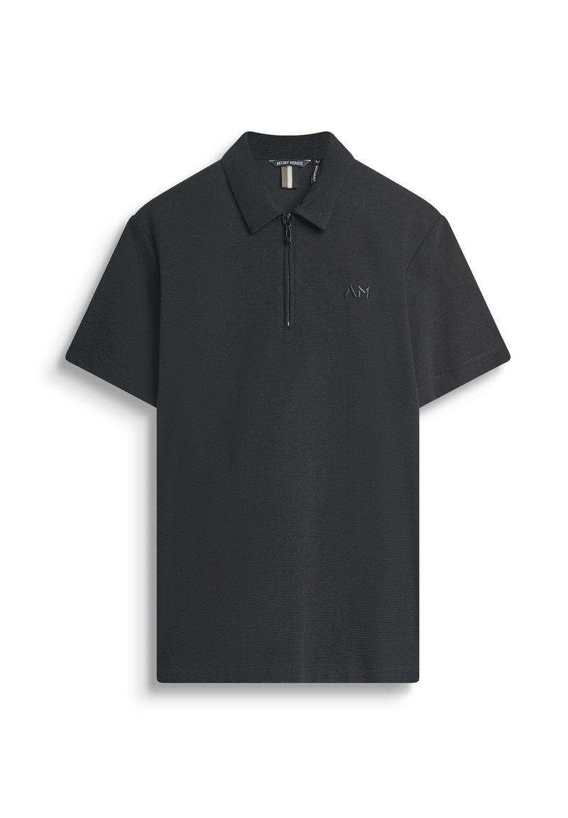 Polo negro con cremallera corta, tejido texturizado y un pequeño logo en relieve en el lado izquierdo. Diseño de cuello clásico.
