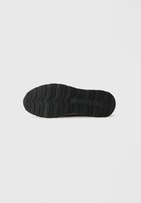 Talpa de cauciuc negru a unei încălțări, având un model de profil în zigzag și un logo de marcă în relief. Texturată pentru aderență și durabilitate.
