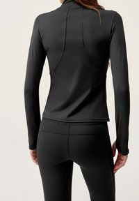 Svart sportigt linne med långa ärmar och hög krage, tillverkat av ett mjukt, stretchigt tyg. Har en figurnära silhuett och sömmar som detaljer.