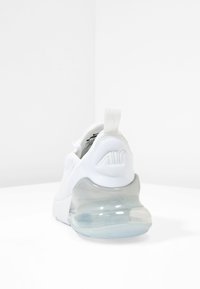 Fehér sneaker, textúrált felsőrésszel, műanyag sarokfuttatóval és átlátszó légpárnás talppal, hátul logós részlettel.