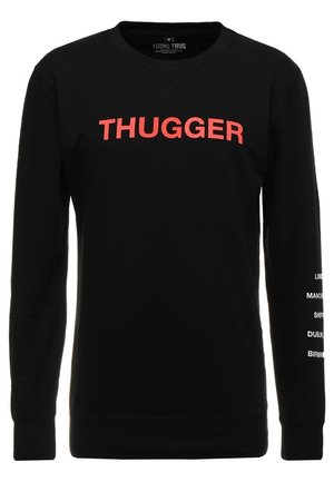 Czarna bluza z długim rękawem z czerwonym napisem „THUGGER” na piersi oraz białymi nazwami miast drukowanymi pionowo na prawym rękawie.