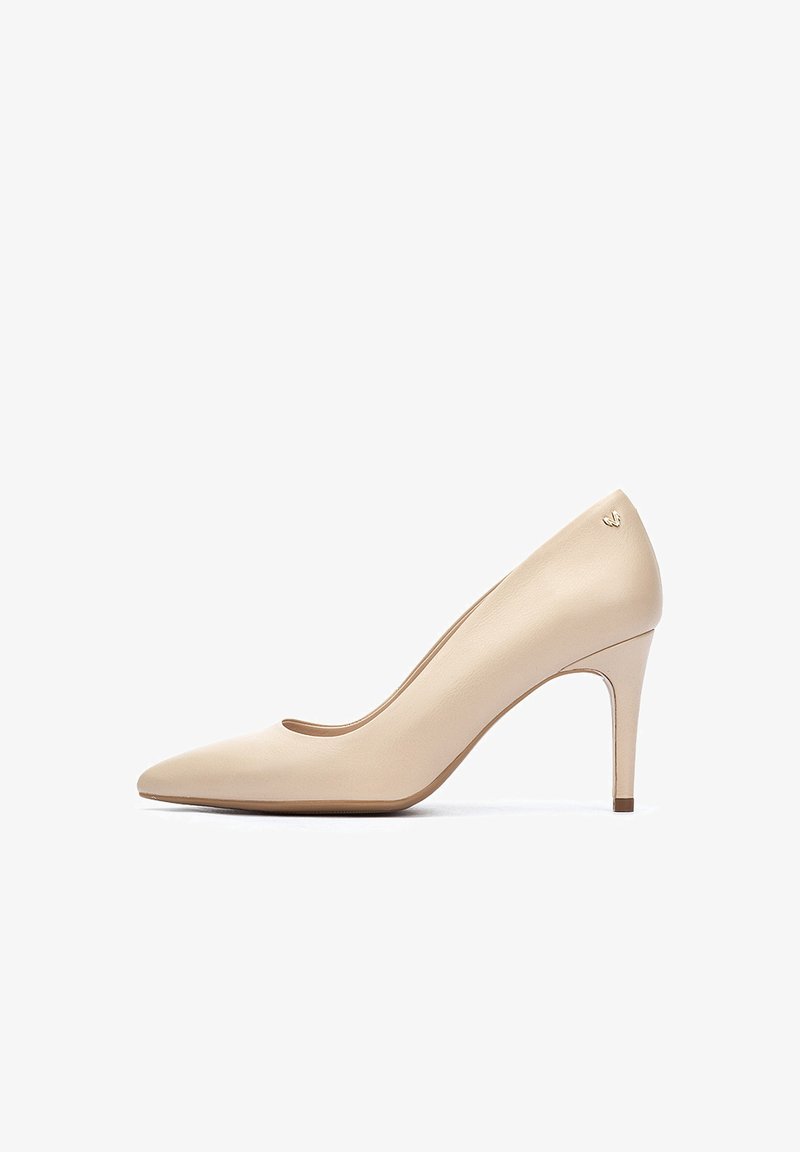 Pump beige in pelle con tacco alto, punta affusolata, texture liscia e un sottile accento del logo dorato vicino al tallone.