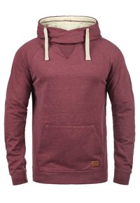 Burgundy hoodie i mjukt tyg med en känguruficka, dragsko-hette i krämfärg och en liten märkesläderpatch vid midjan.