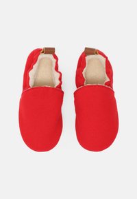 Czerwone buty z tkaniny z miękką wyściółką, elastycznym otworem i brązowymi skórzanymi akcentami. Zaokrąglony kształt z gładką fakturą.