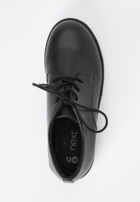 Chaussure en cuir noir avec bout rond, semelle plate et design à lacets. L'étiquette intérieure indique la taille 12F. Texture lisse avec un minimum de surpiqûres.