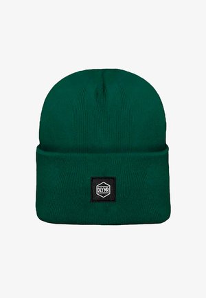 Grüne Strickmütze aus weichem, dehnbarem Material. Mit umgeschlagenem Bündchen und einem schwarzen rechteckigen Etikett mit weißem Text.