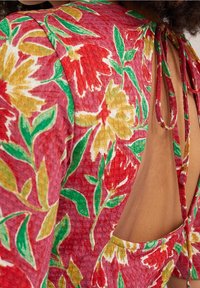 Kwiatowa sukienka w odcieniach różu, czerwieni i żółci z zielonymi akcentami; posiada fakturowany materiał, odkryty tył oraz zapięcie na krawat przy szyi.