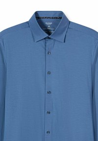 Hellblaues Hemd mit Kragen aus Jersey-Stoff. Verfügt über eine Knopfleiste mit Knöpfen in der Stofffarbe und einen gemusterten Innenkragen.