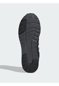 Semelle extérieure de chaussure de sport noire en matériau en caoutchouc, avec un motif texturé pour une meilleure adhérence et un logo distinctif au niveau du talon.