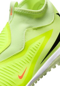 Scarpa atletica giallo-verde con tomaia texturizzata, caratterizzata da un logo Nike arancione brillante, cuciture lisce e una suola pattern per trazione.