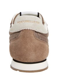 Zapatilla de ante marrón con suela blanca, que presenta una parte superior de tela color beige y detalles en negro. "PORTOBELLO RD" grabado en el talón.