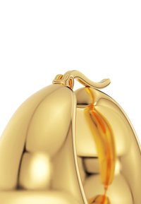 Guldfärgad dekoration med en slät, reflekterande yta. Har en elegant, böjd design och ett litet, intrikat handtag högst upp.