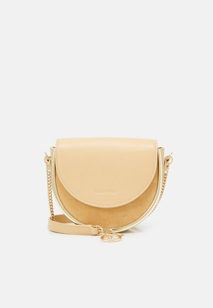Petit sac bandoulière beige en forme de demi-lune, en cuir et suède, avec une bandoulière chaîne dorée et un charm rond doré à l'avant.