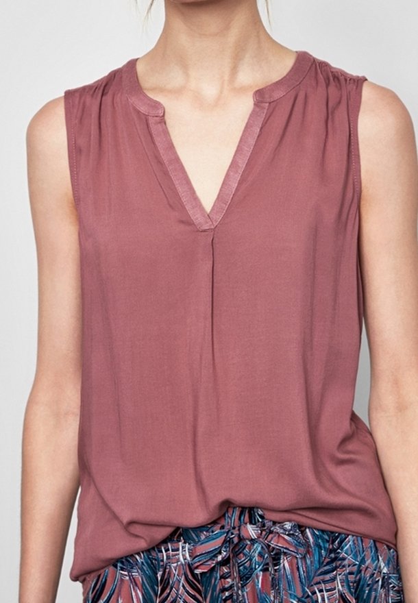 Sleeveless mauve V-neck blouse paired with patterned blue and pink pants tied with a front bow.