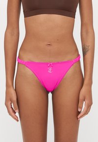 Bas de bikini rose avec un nœud décoratif et un détail de logo, présentant des côtés froncés et une texture lisse. Conçu pour un ajustement serré.