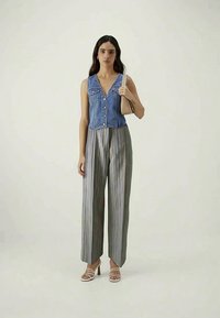 Denim sleeveless top with button front, paired with wide-leg striped trousers in muted colors, and strappy high-heeled sandals.