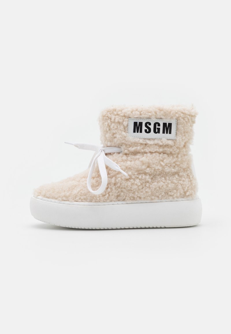 Botas de tornozelo forradas a pêlo bege com solas de borracha brancas. Apresentam um fecho com atacadores e um emblema MSGM preto e branco na lateral.