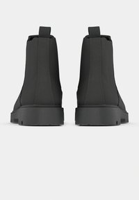 Botines negros hasta el tobillo con un acabado liso, que presentan paneles laterales elásticos y lengüetas. Suelas de goma resistentes con una ligera altura de plataforma.