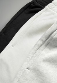 Tre par sweatpants i svart, vitt och ljusgrått. Mjuk bomullstyg, elastisk midja och sidofickor. Snygga sömnadsdetaljer.