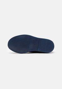 Semelle de chaussure bleu marine en caoutchouc texturé, dotée de rainures horizontales pour l'adhérence et d'un indicateur de taille estampé.