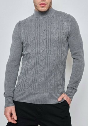 Pull en maille grise avec un col montant, motif en torsades, manches et taille côtelées, fabriqué à partir d'un matériau doux.