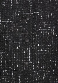 Czarna tkana marynarka z teksturowanej tkaniny z metalicznymi akcentami, sześcioma wyraźnymi guzikami i zarysowanym fasonem.