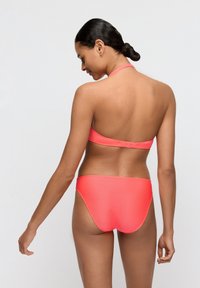 Completo bikini color corallo a coste, composto da top con design a collo alto e chiusura a fibbia, caratterizzato da una finitura liscia e uno stile minimalista.