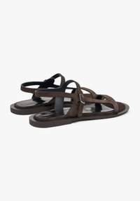 Bruine suède sandalen met meerdere kruiselings banden, een platte zool en een zilveren gesp detail op de enkelband. Gladde afwerking aan de binnenkant.