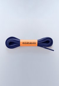 Lacets de chaussures bleu foncé enroulés, maintenus par une bande de papier orange étiquetée « NAPAPIJRI » sur un fond gris clair.