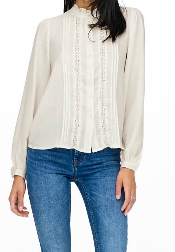 Helles beiges Blusenshirt mit hohem Kragen, langen Puffärmeln, Druckknopfverschluss auf der Vorderseite und vertikalen Spitzenverzierungen entlang des Oberteils.