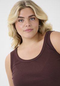 Burgundy sleeveless top with a ribbed texture and a rounded neckline, featuring wide shoulder straps and a close fit.