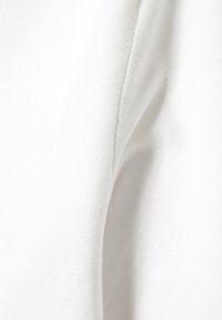 Tissu blanc avec une surface lisse et légèrement texturée, présentant des plis doux et un subtil éclat. Le matériau semble léger et respirant.