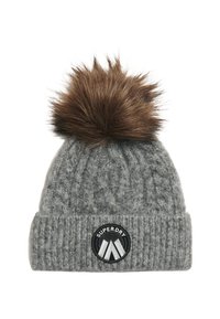 Gorro de punto gris con diseño de cable, que presenta un pompon de peluche marrón encima y un parche circular negro con el logotipo "SUPERDRY".