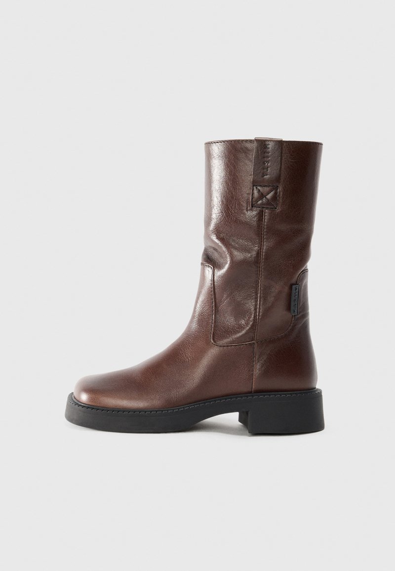 Brown leather ankle boot with a smooth finish, rounded toe, chunky black sole, and a textured back panel featuring stitching detail.