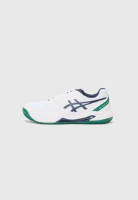 Weißer Sportschuh mit marineblauen Akzenten und grüner Sohle. Mit einem Obermaterial aus Mesh, Schnürdesign und Logo an der Seite.