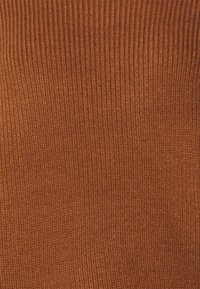 Tkanina w kolorze rdzy dzianinowa, z teksturowanym wzorem prążków. Materiał wydaje się miękki i elastyczny, odpowiedni do odzieży, takiej jak swetry czy bluzki.