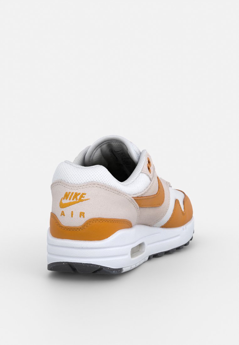 Nike Air Max sneaker in beige, wit en oranje, met een bovenwerk van suede en mesh, een gevoerde zool en een zichtbare luchtunit in de hak.