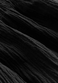 Primer plano de tela negra acanalada con textura visible y pliegues suaves que crean un patrón ondulado.