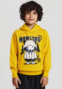 Felpa gialla con design grafico che presenta un personaggio dei cartoni animati in un cappotto morbido e alberi. Maniche lunghe e tasca frontale.