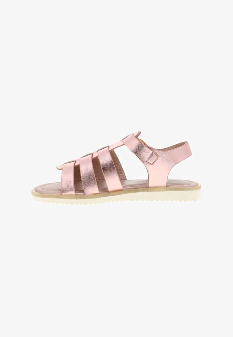 Sandalia plana metálica color oro rosa con múltiples tiras y una suela blanca texturizada, con una correa de soporte para el tobillo con hebilla.