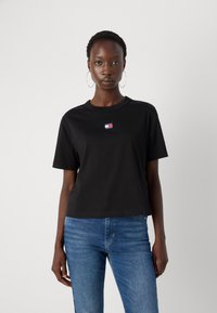 Tricou negru din bumbac cu guler rotund, mâneci scurte și o mică etichetă cu logo colorat pe piept. Purtați-l cu blugi din denim albastri.