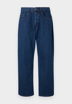 Jean denim bleu foncé à jambes droites avec fermeture devant par bouton et zip, passants de ceinture et deux poches avant sur fond uni.