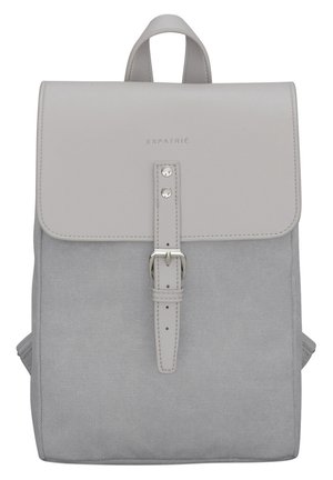 Sac à dos en tissu gris avec rabat en cuir gris clair, fermeture à boucle et poignée supérieure, marqué "EXPATRIÉ" sur le rabat.