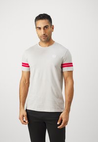 Lys grå treningstrøye med røde striper på ermene og en liten logo på brystet, tettsittende design, bomullsmateriale.