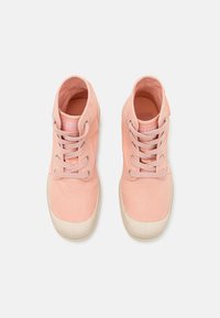 Zapatillas altas de lona rosa con cordones tono sobre tono, puntera de goma y logo en la lengüeta. Presentan una superficie texturizada y una forma redondeada.