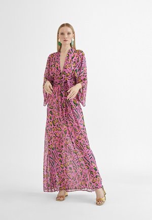 Vestido maxi en una tela ligera y translúcida con un estampado animal en rosa, verde y negro. Con mangas largas y una cintura ajustable. Sandalias de tacón doradas.