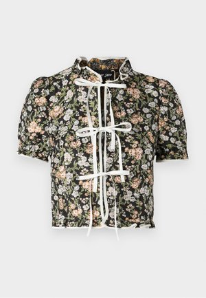 Kortærmet bluse med sort blomsterprint, hvid sløjfesløjfe lukning og samlede skuldre. Dekorativ bølget kant med struktureret stof.