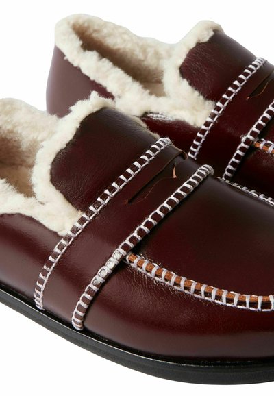 Scarpe slip-on bordeaux in pelle, con fodera in pelliccia sintetica, dettagli di cucitura bianca e design testurizzato.