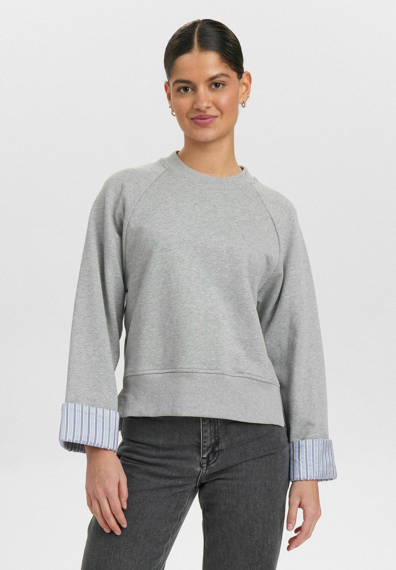 Grå sweatshirt med rund hals, raglanärmar och randigt tyg vid ärmsluten. Har en avslappnad passform och mjuk textur.